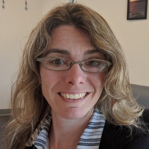 Samantha Stevenson wears glasses and a black jacket over a striped collared shirt